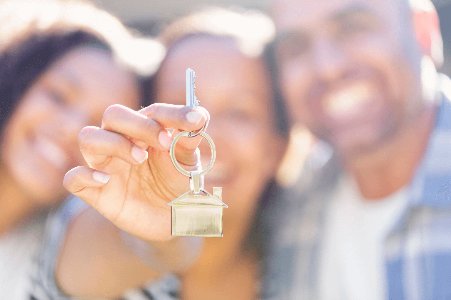 Smiling siblings holding house keys after selling inherited home
