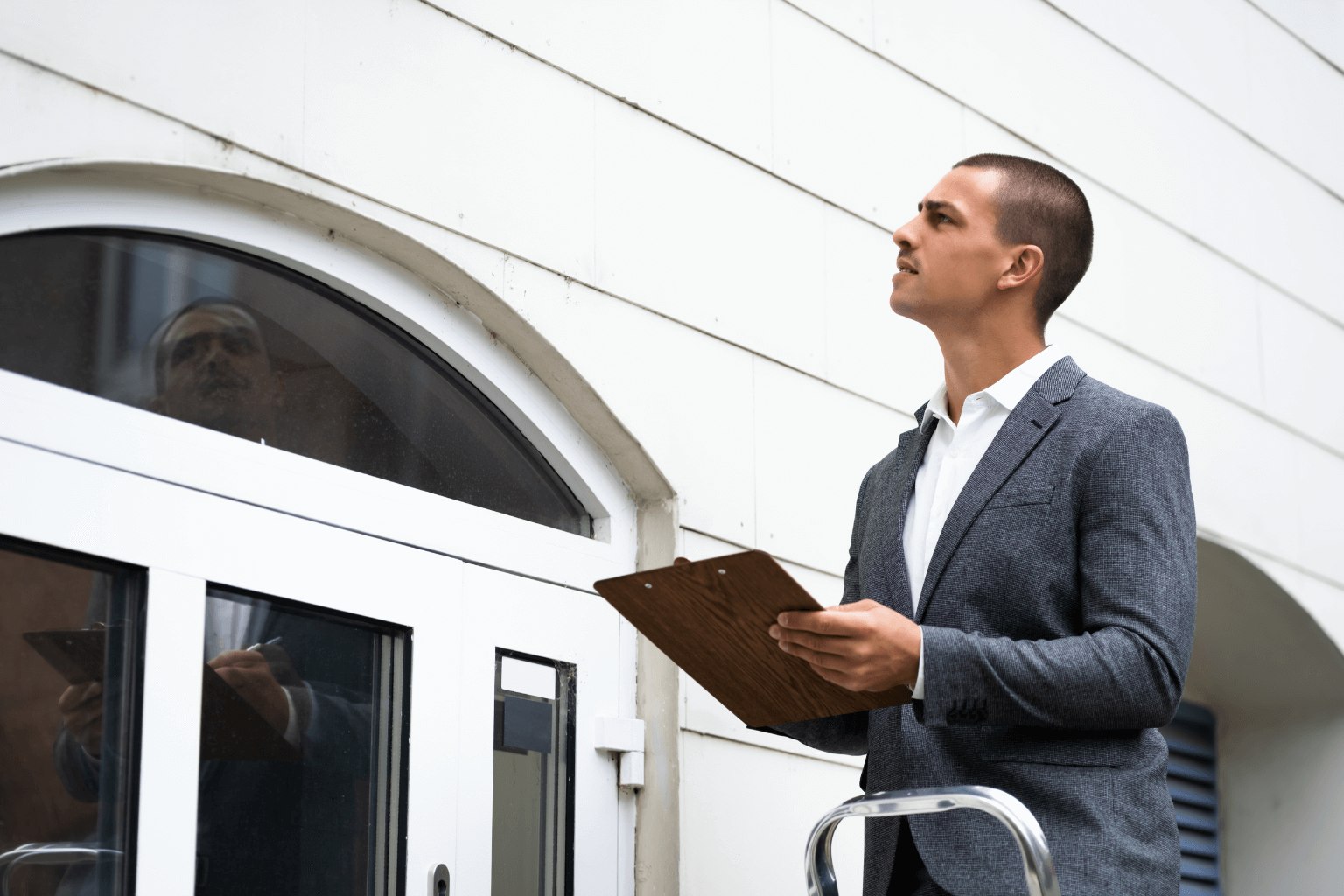Appraiser inspecting a home exterior with clipboard