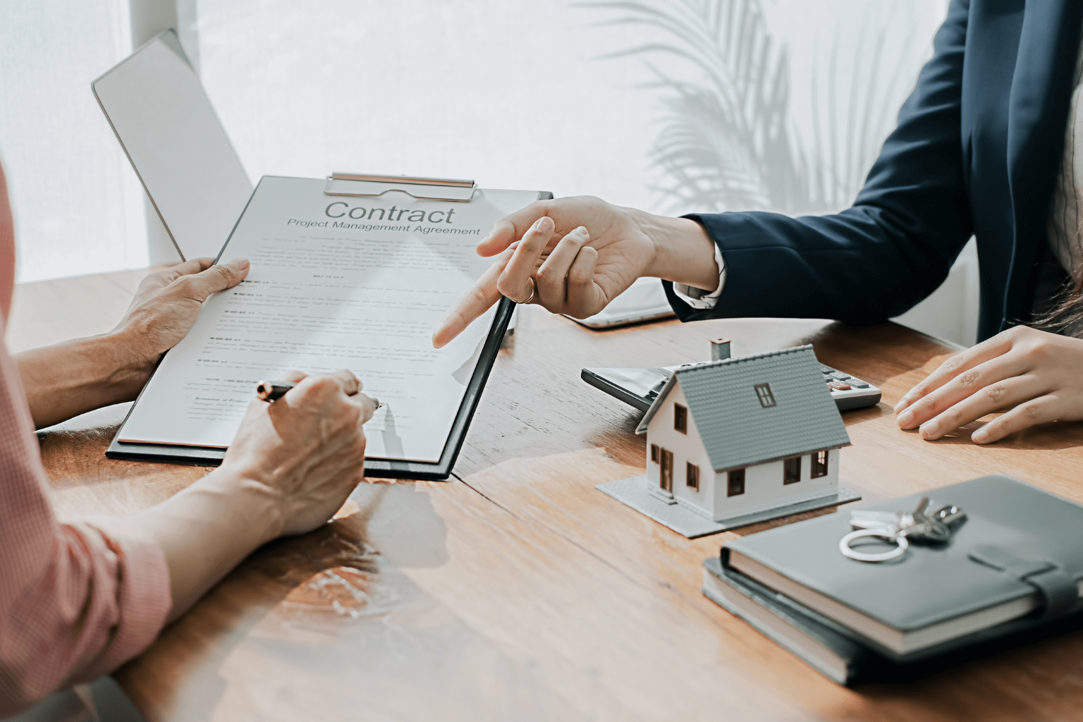 Homeowner signing legal documents with house keys on table