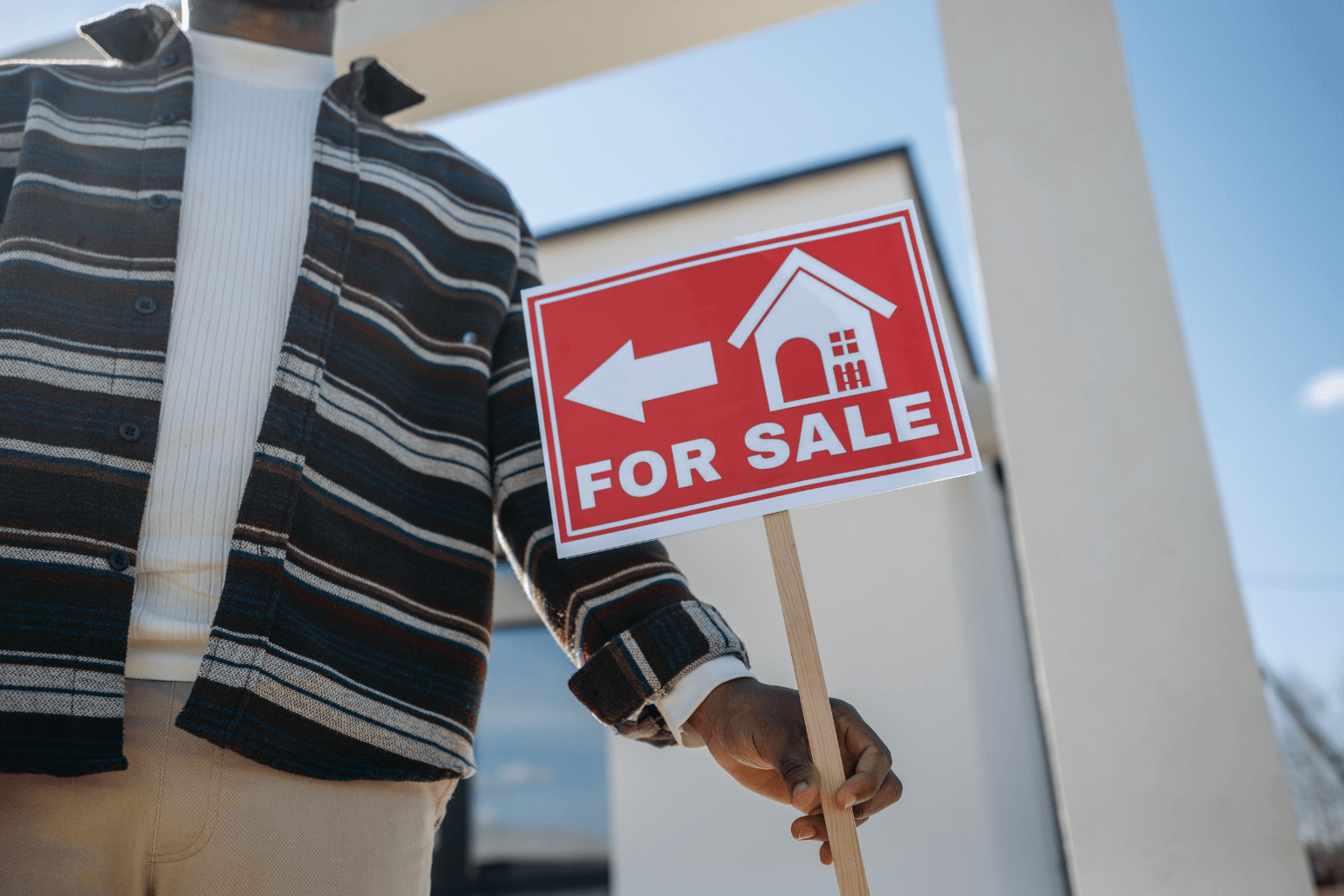 Person with a for sale sign in the front yard