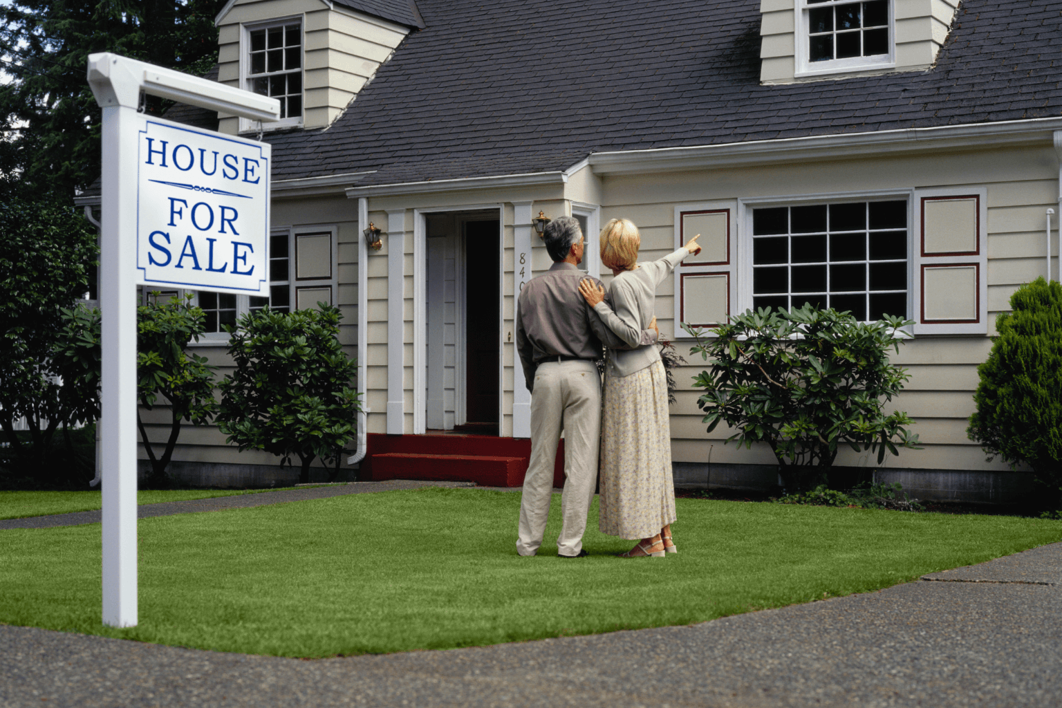 Siblings standing outside inherited house discussing sale