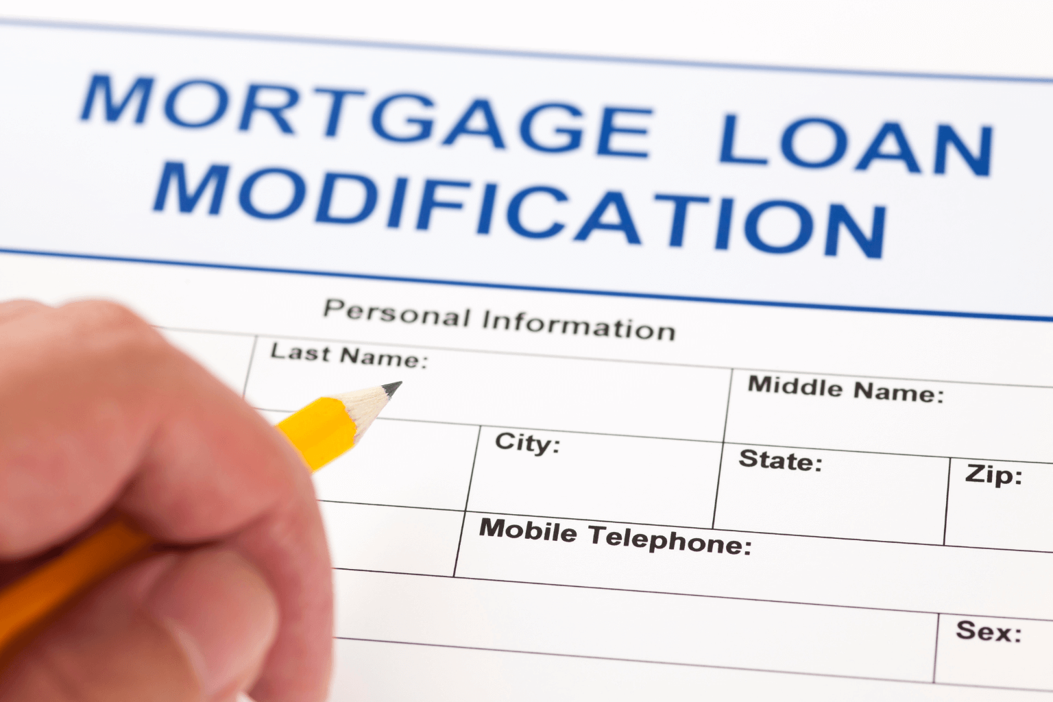 Person filling out loan modification forms at a desk