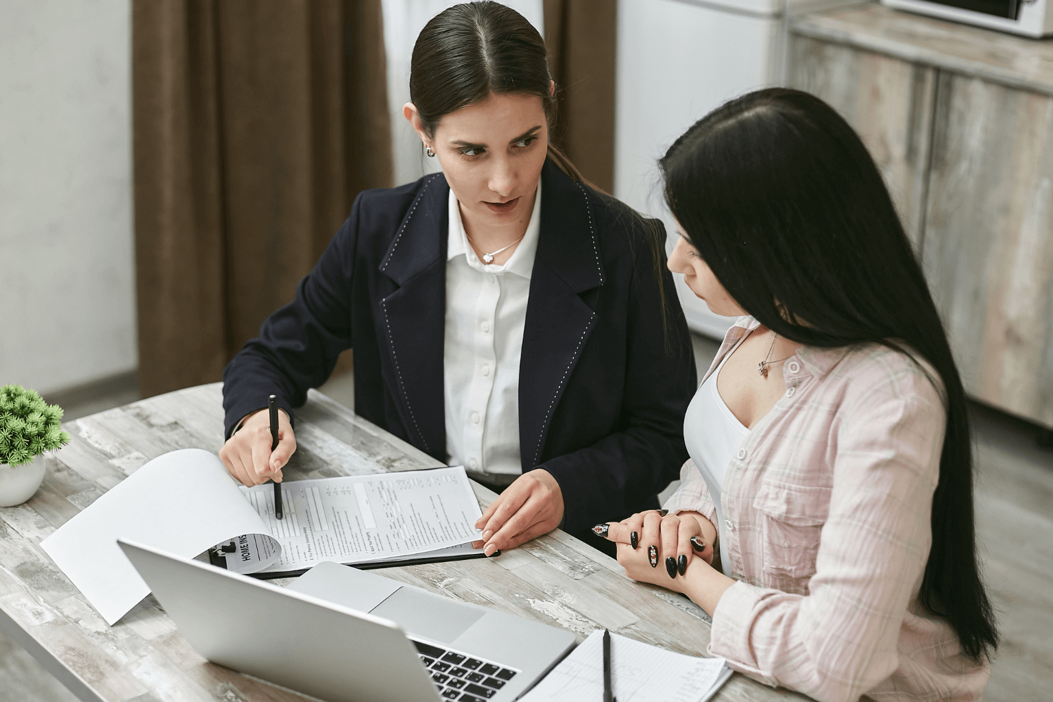 Two people negotiating a home sale with documents on the table