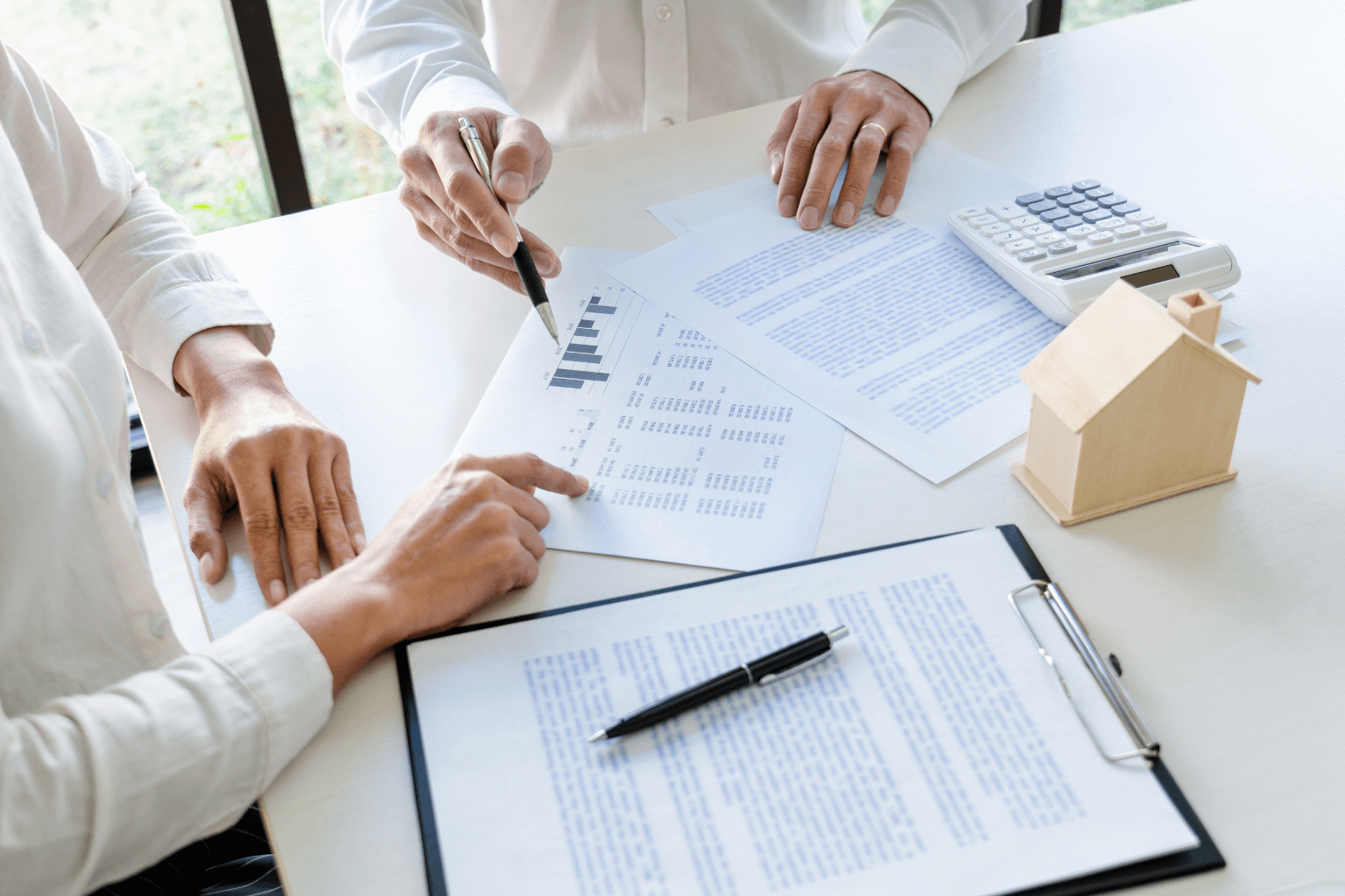 Real estate agent and homeowner reviewing housing prices on paper