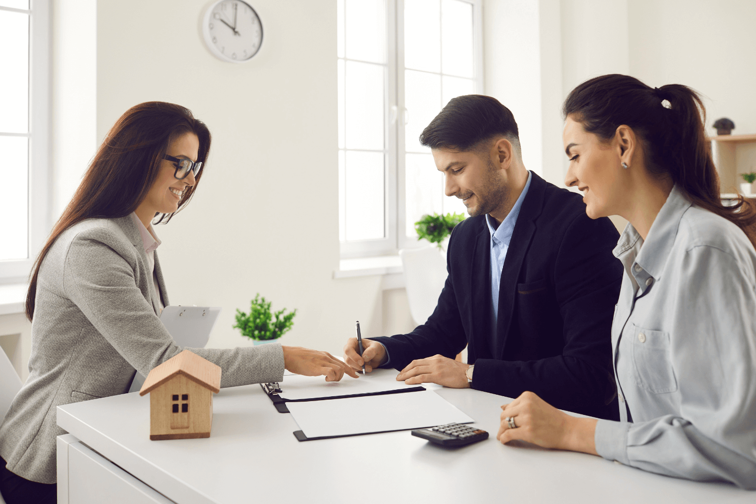 Buyers and seller signing real estate documents with agent