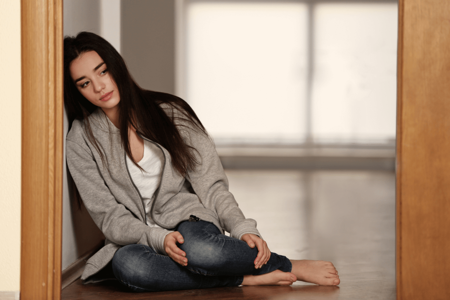 Woman sitting alone looking emotional in empty room