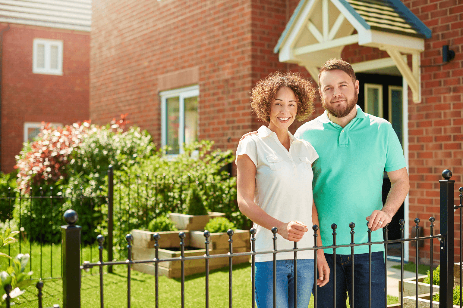 Happy homeowners standing outside a repaired house