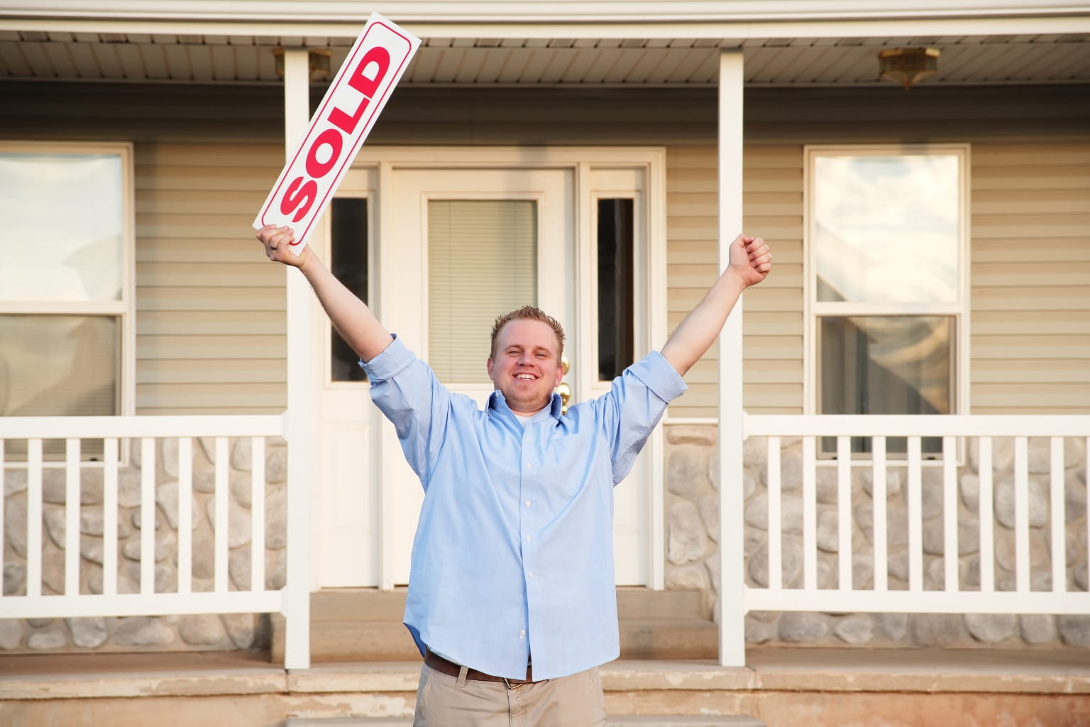 Happy homeowner holding a "sold" sign