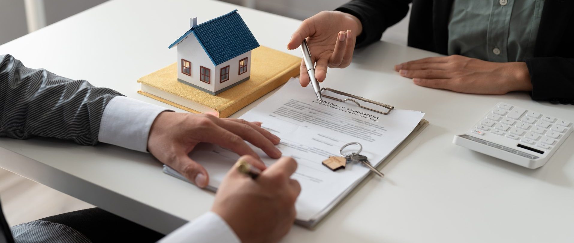 Real estate agent holding house key to his client after signing