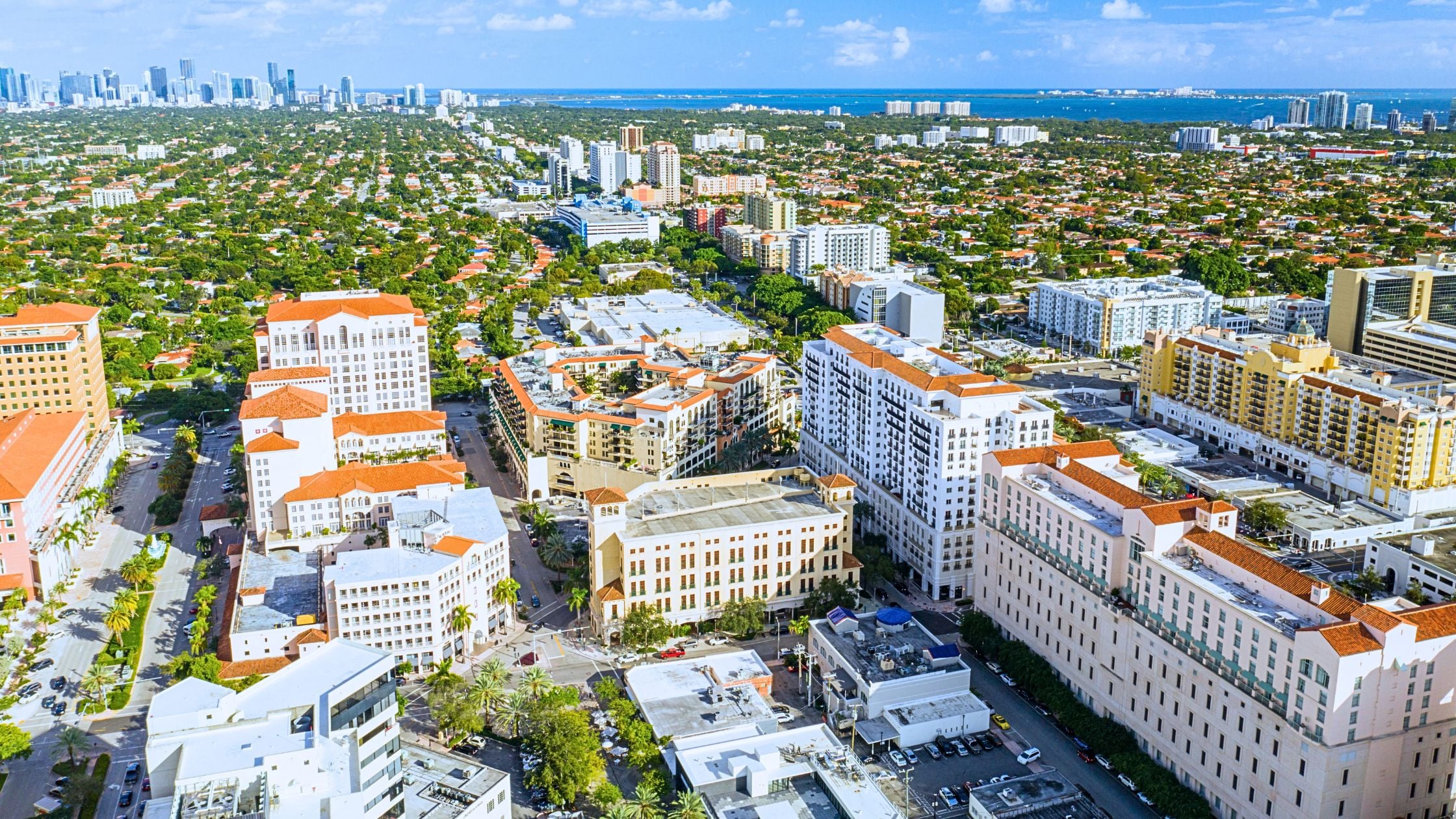 Mediterranean Revival home under tree canopy representing living in Coral Gables Miami lifestyle