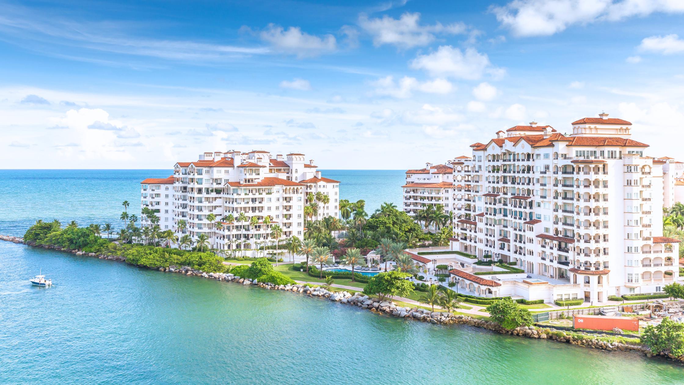 Aerial view of Fisher Island Miami showing luxury condo towers, marina, and ferry access to the private island.