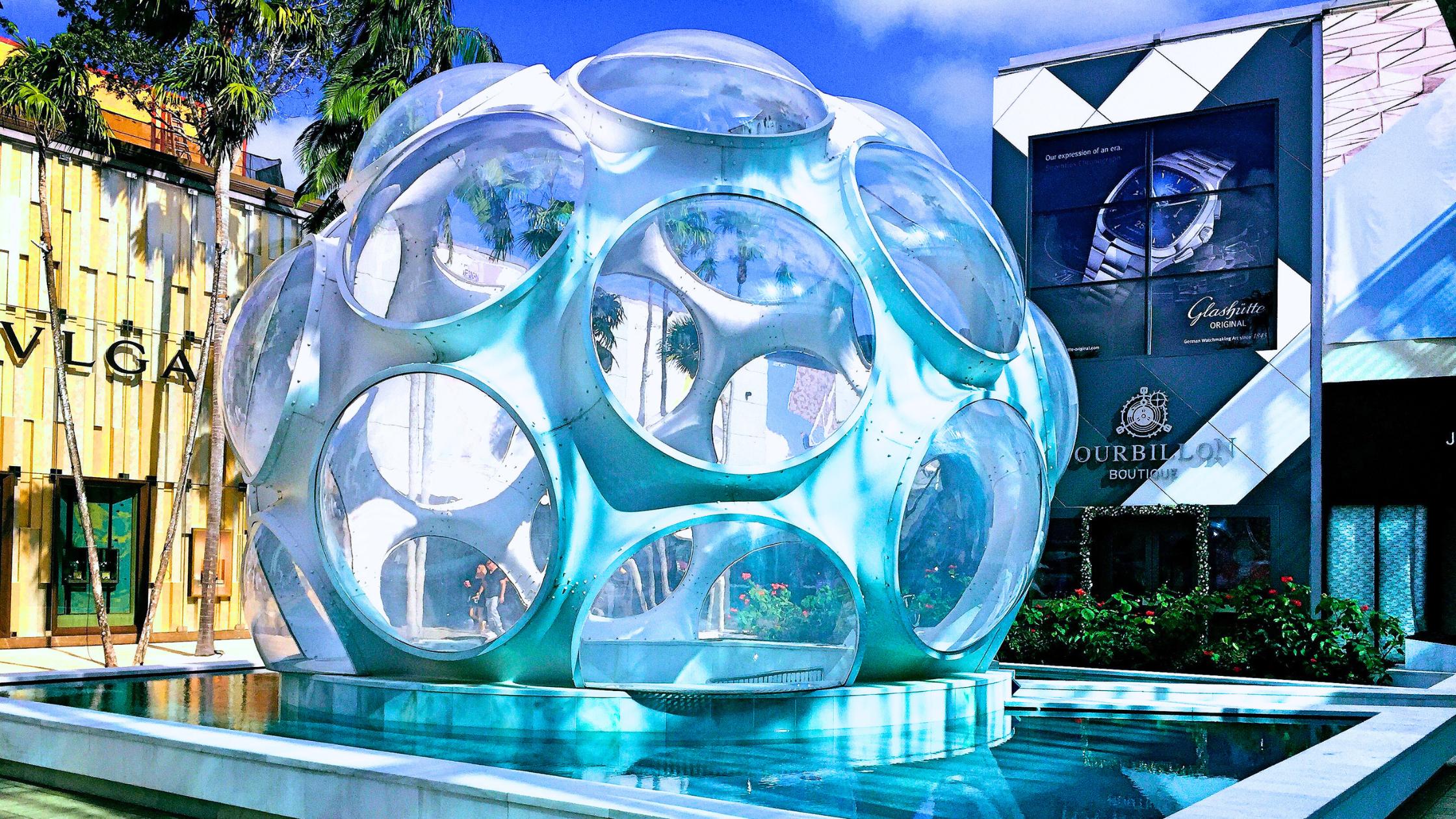 Miami Design District street with luxury retail storefronts and pedestrian art installations under afternoon sun