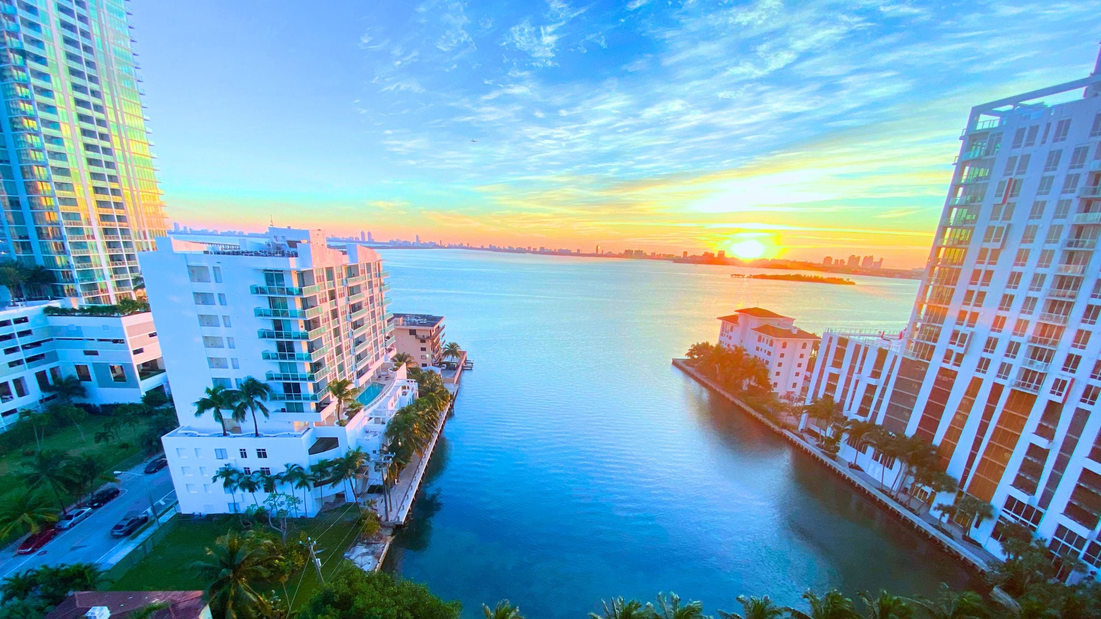 Second home owner on a Miami bayfront condo balcony at sunrise, coffee in hand.