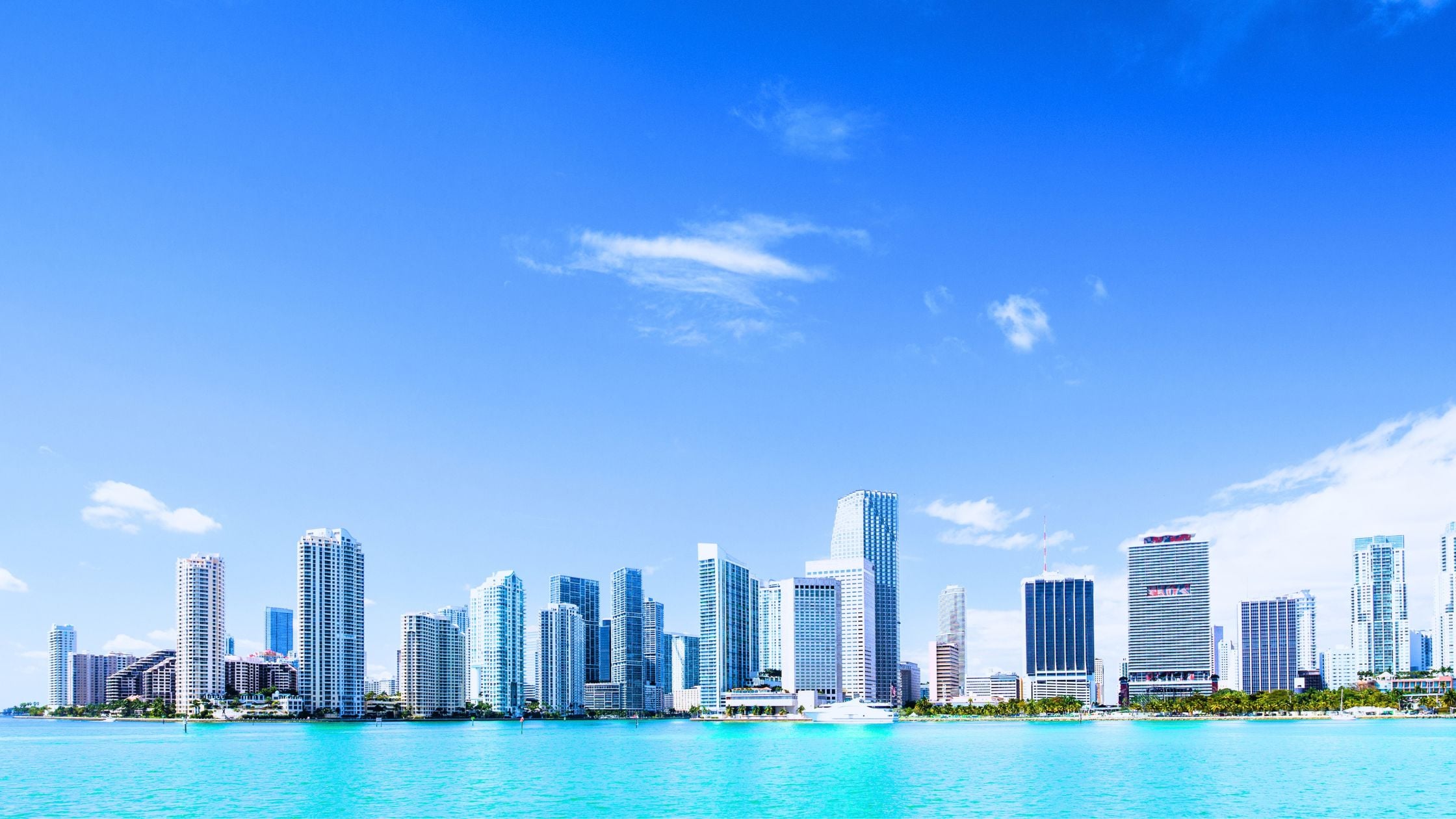 New construction tower with crane beside established condo buildings along Biscayne Bay in Miami