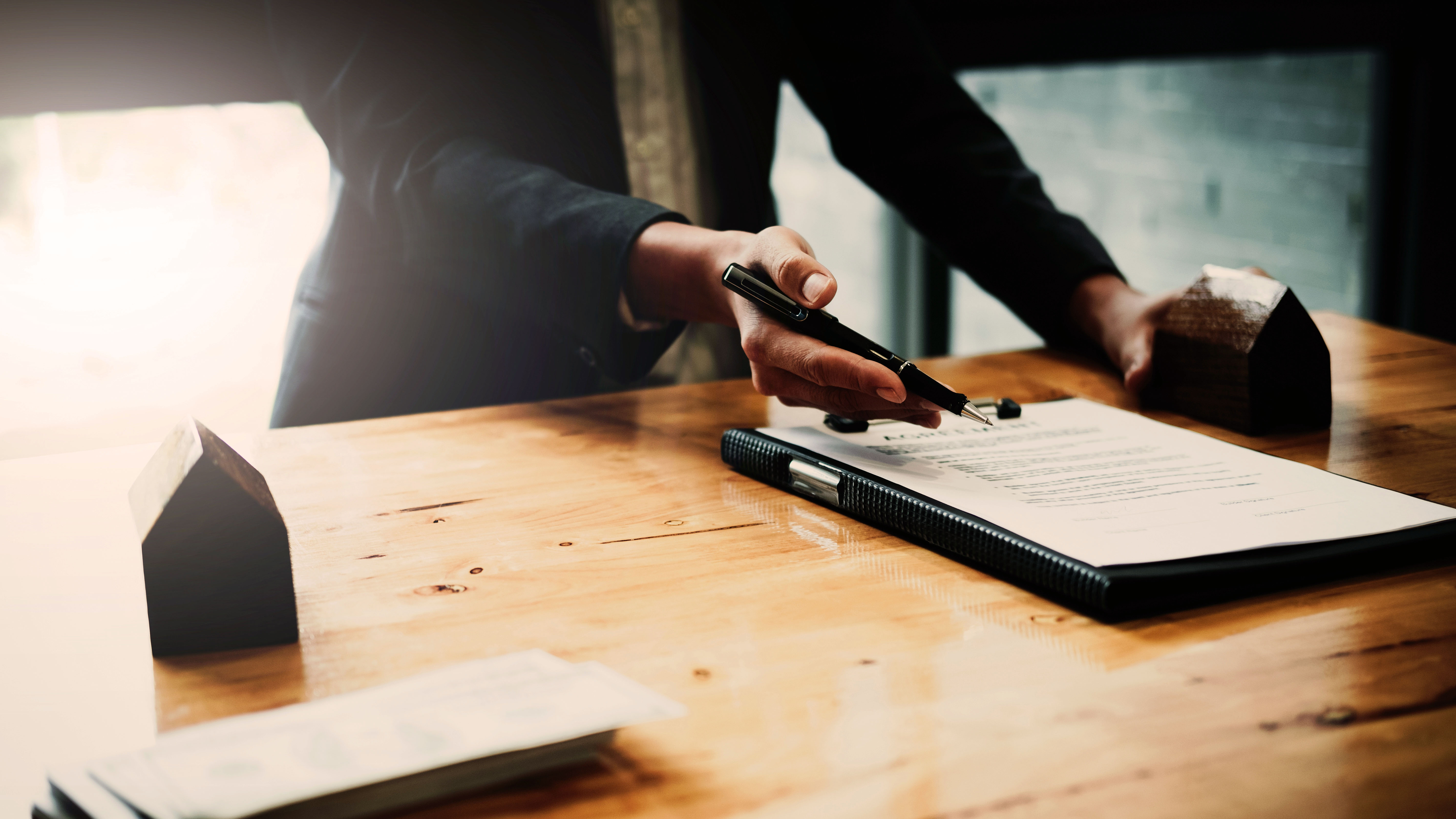 businessman offer to signs contract with home architectural model at his office