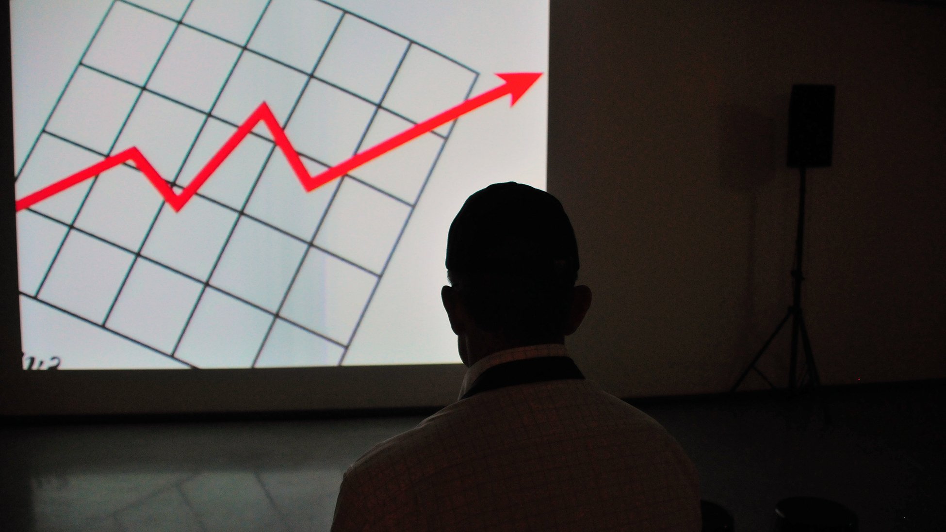 Man looking at presentation of a graph with an arrow going up