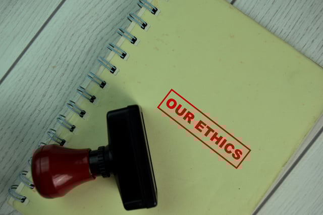 Red Handle Rubber Stamper and Our Ethics text isolated on Brown burlap laying on table