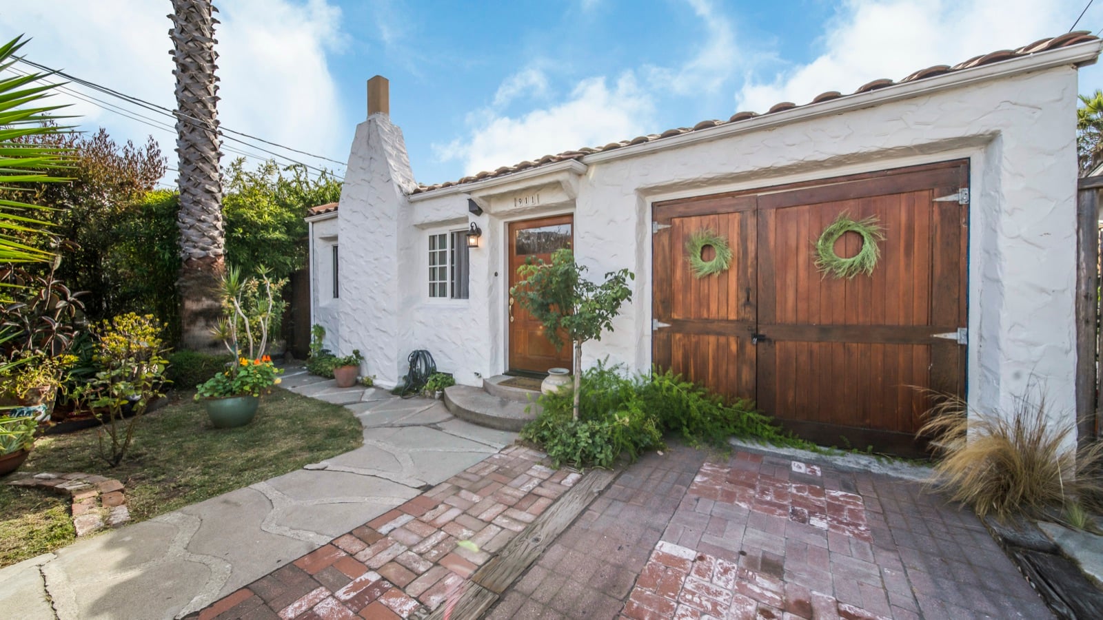Front of the house, a white stucco bungalow with redwood garage doors