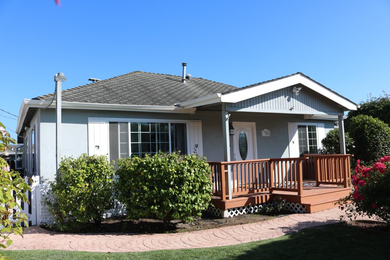Front of the main house: white single-story house with roses, picket fence and arbor