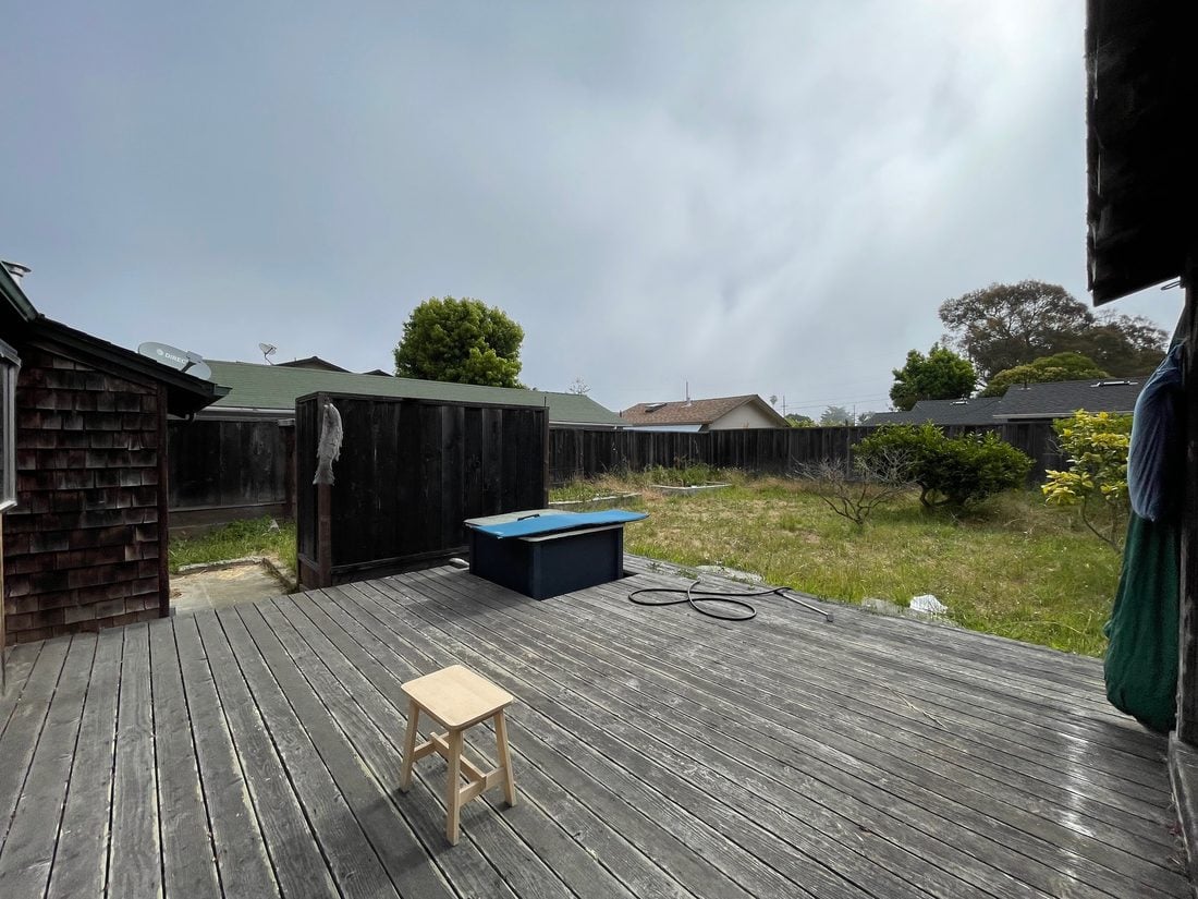 Deck before: cluttered with a covered hot tub under gray skies