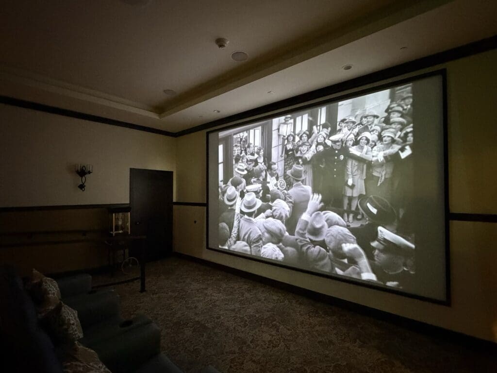 Movie theater at Aegis Living San Rafael with a large wall screen showing a black and white film and dark reclining seats