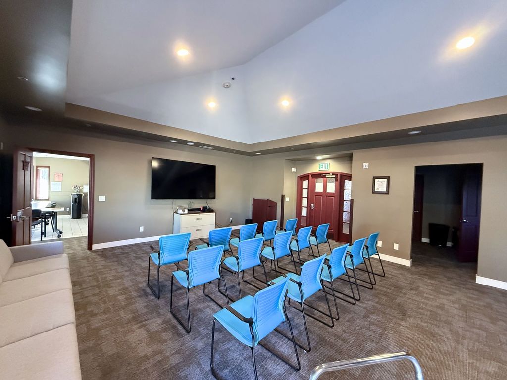 Meeting room with rows of chairs, a podium and a large TV for presentations at Hearts & Minds Activity Center in San Jose
