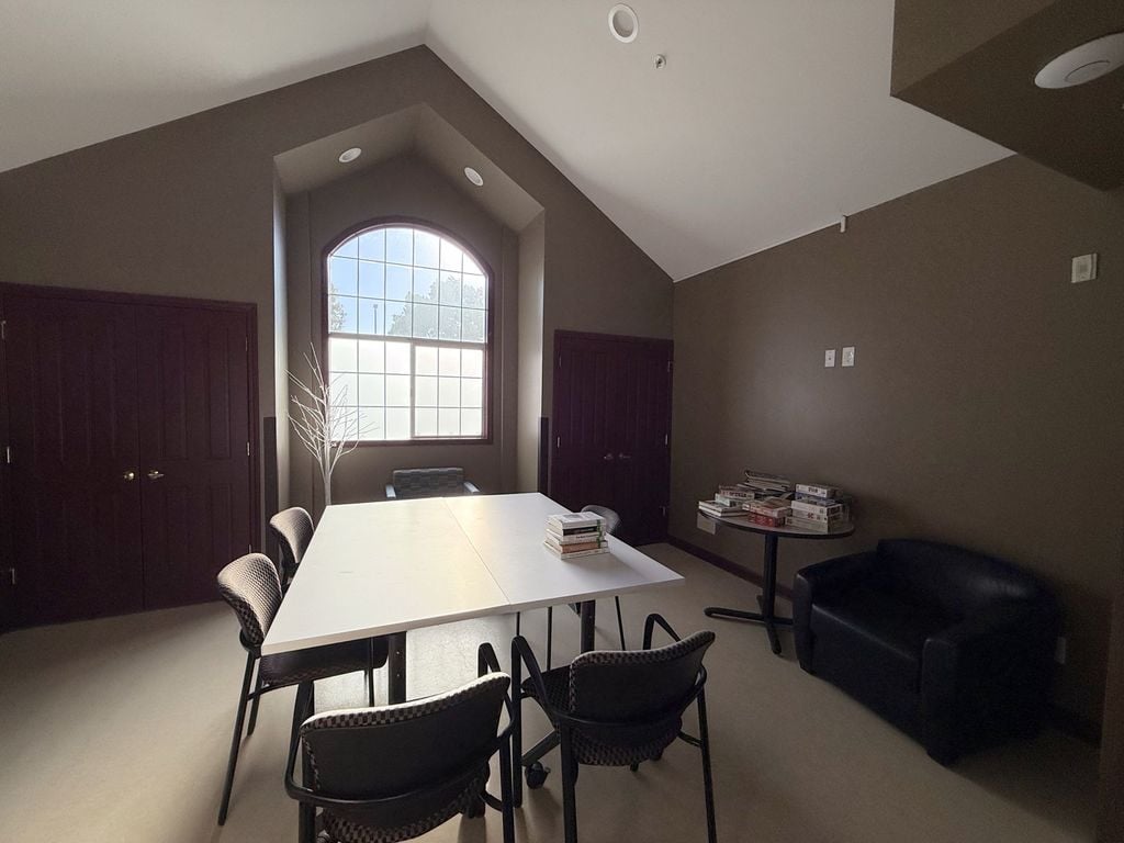 Reading and puzzle room with a vaulted ceiling, arched window, books and jigsaw puzzles at Hearts & Minds Activity Center in San Jose