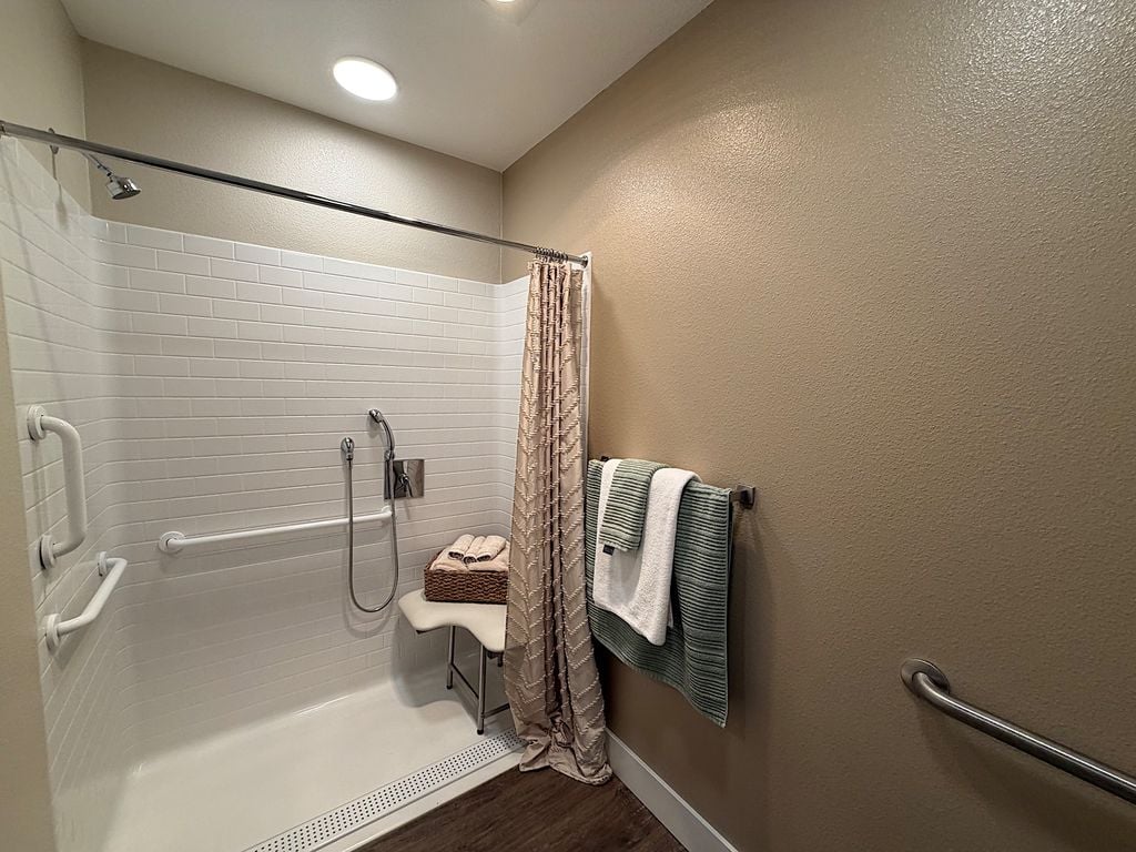 Low-threshold walk-in shower with grab bars, handheld shower and seat at Ivy Park at San Tomas