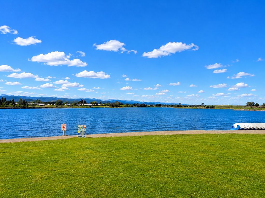 Wide grassy lawn overlooking the 50-acre Shoreline Lake in Mountain View with the Santa Cruz Mountains on the horizon