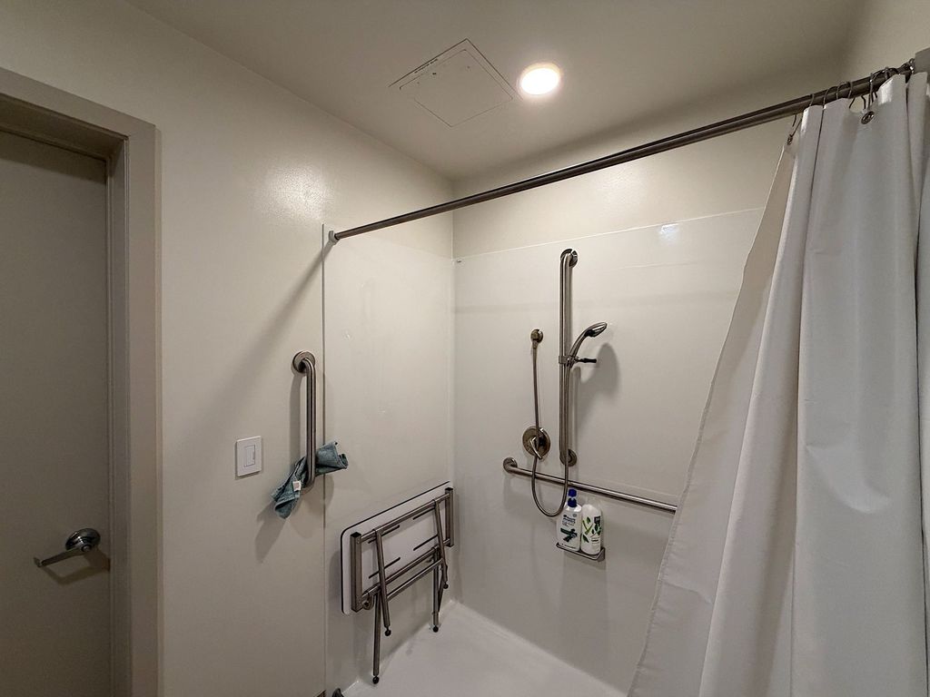 Roll-in shower with fold-down seat, grab bars and handheld showerhead at Villa Toscana Memory Care