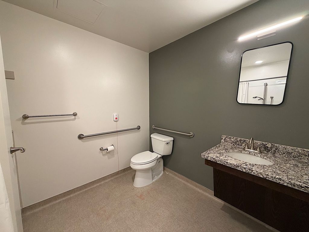 Resident bathroom with grab bars, emergency call button and granite vanity at Villa Toscana Memory Care