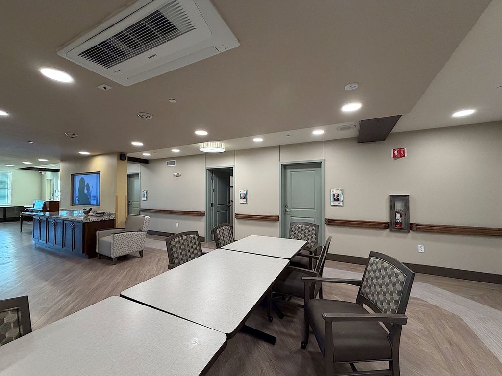 Memory care common area with dining tables, piano and resident doors with memory boxes at Villa Toscana in Mountain View
