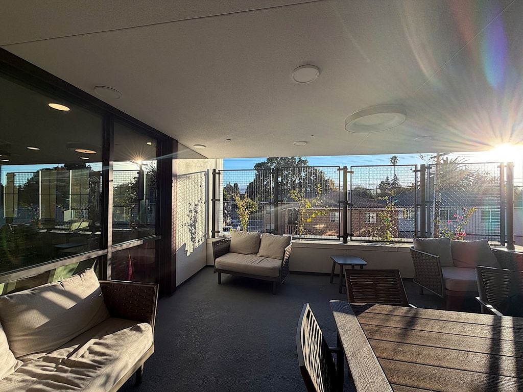 Covered patio with outdoor sofas and dining table behind decorative screens at Villa Toscana Memory Care