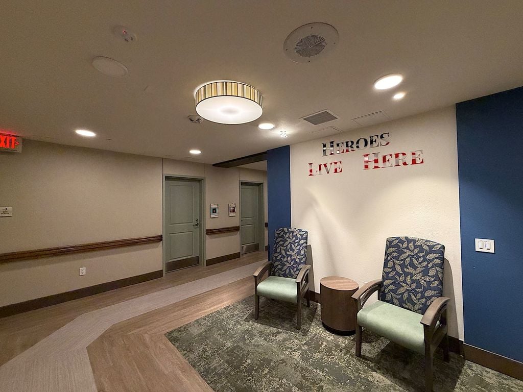 Heroes Live Here veterans recognition wall and seating alcove in a hallway at Villa Toscana Memory Care