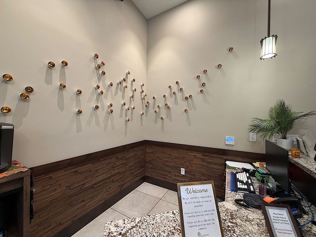 Reception desk with gold ceramic wall art at Villa Toscana Memory Care in Mountain View