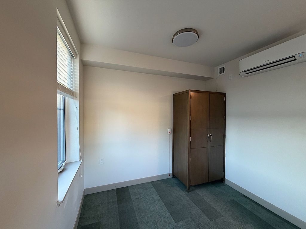 Resident suite with wardrobe, ductless heating and cooling unit and emergency pull cord at Villa Toscana Memory Care