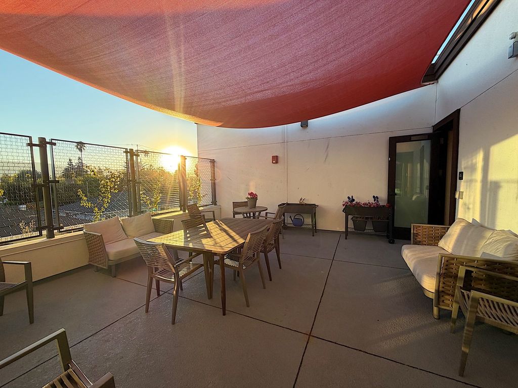 Outdoor terrace with shade sail, patio dining set and raised garden planters at Villa Toscana Memory Care