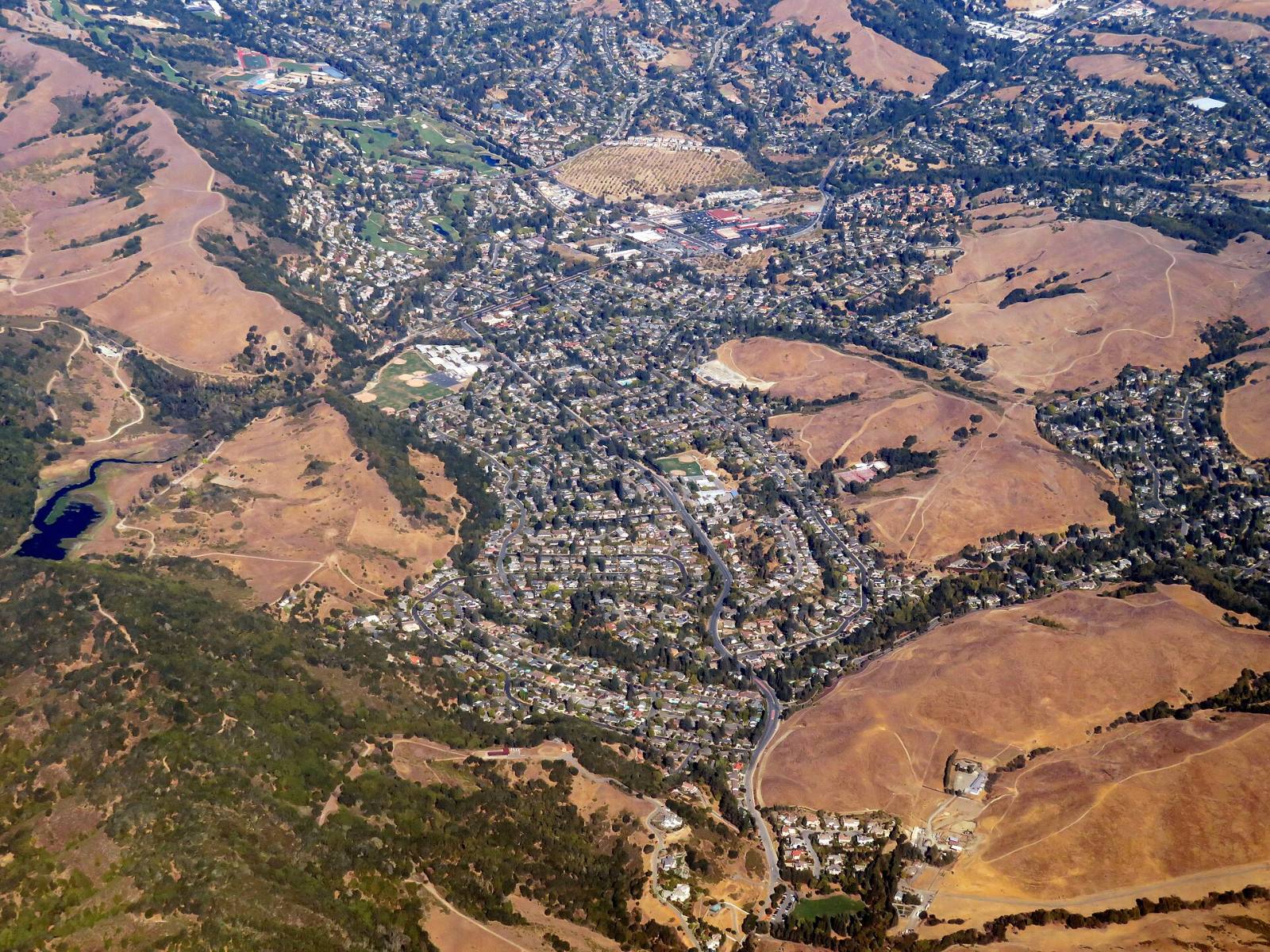 Aerial view of Moraga, California, with homes below dry grass hills, October 2020