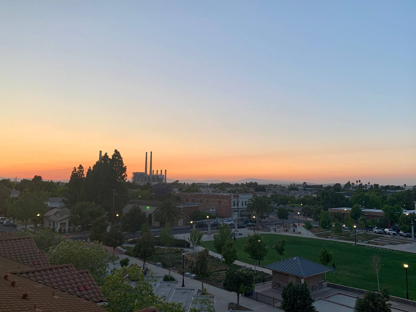 John Buckley Square in Old Town Pittsburg at dusk, with power plant stacks in the background, 2023