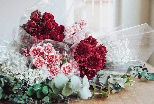 Bouquets of red roses, carnations, chrysanthemums, and baby's breath with eucalyptus.