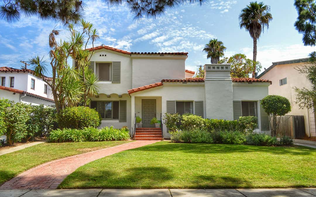 Home Exterior With Green Lawn And Palm Trees In The Distance.