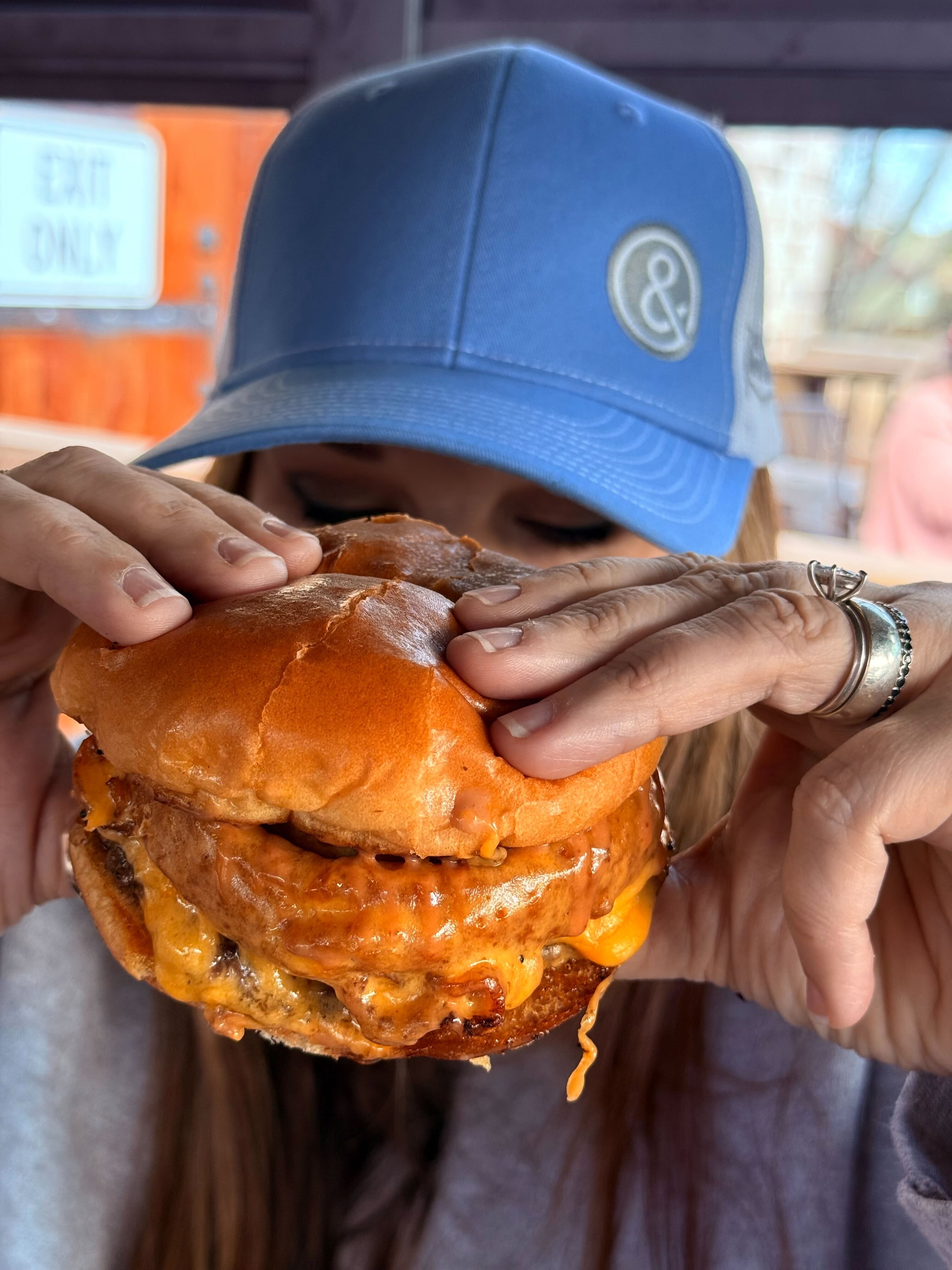 Woman wearing a blue hat enjoying a fresh made burger