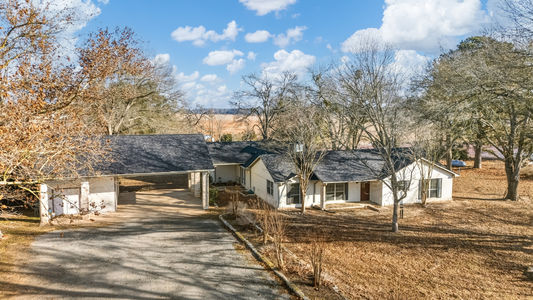 Wide angle photo of the front of the house and carport showing the white brick and dark gray composite roof on 2365 S. FM 46 in Franklin, TX