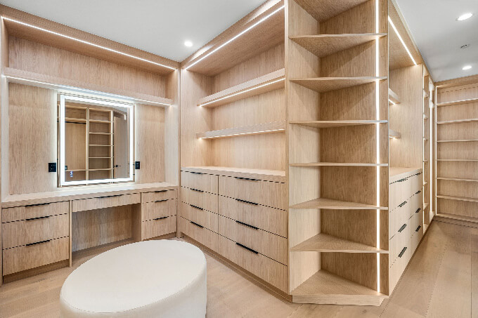 Modern walk-in closet with wooden shelves, drawers, and a vanity mirror, featuring soft lighting and a minimalist design (small)