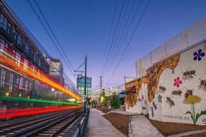 Light-rail train passing South End murals on the Rail Trail