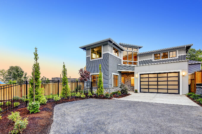 Excellent curb appeal of a Modern craftsman style home accented by landscaping, gray siding, large windows (small)