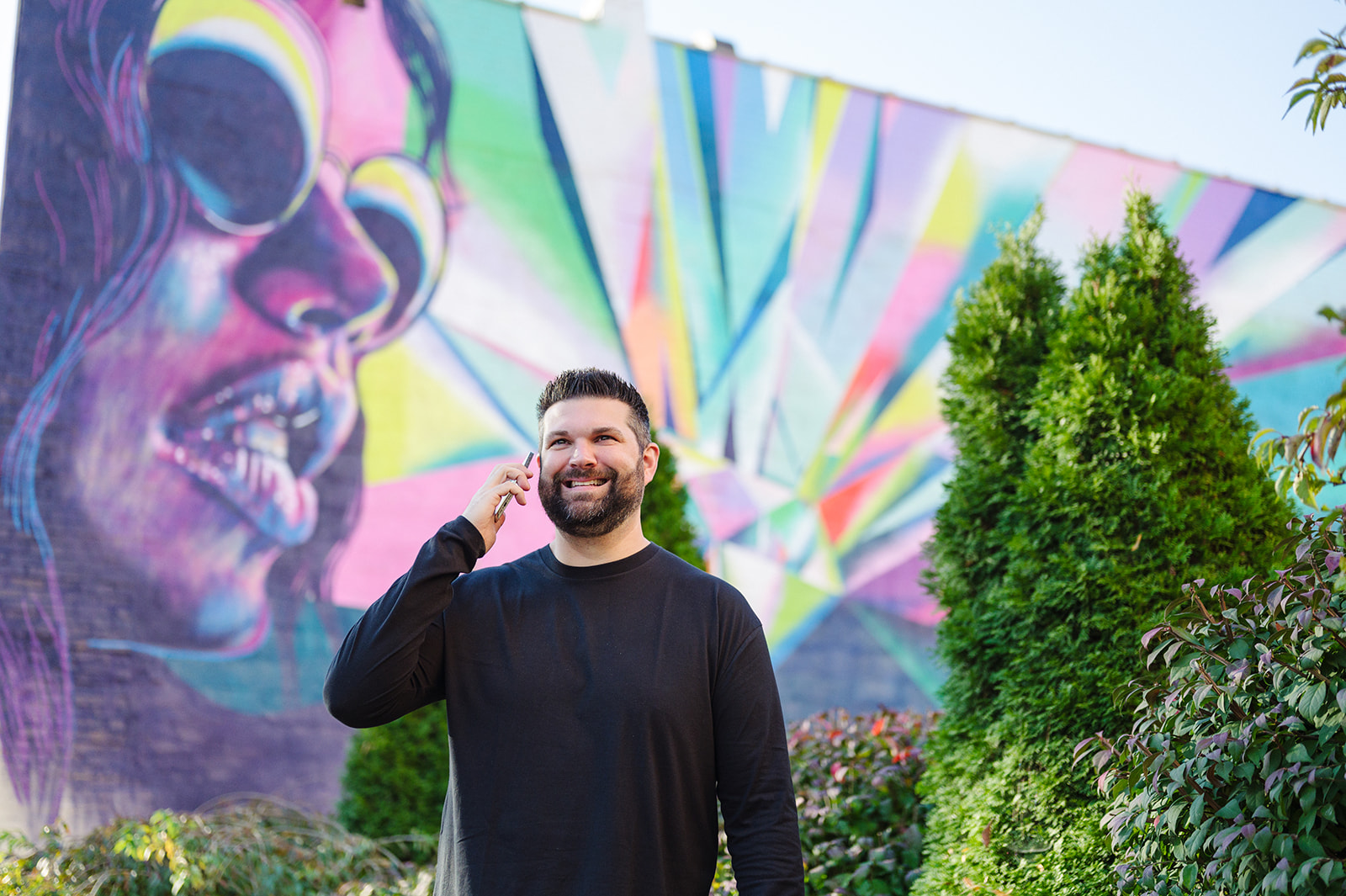 This is a photo of a real estate listing agent on the phone in front of a mural.