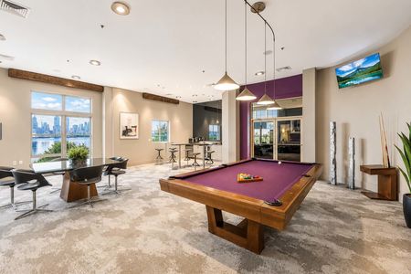 14. 26 Ave Port Imperial Modern lounge with city view and pool table