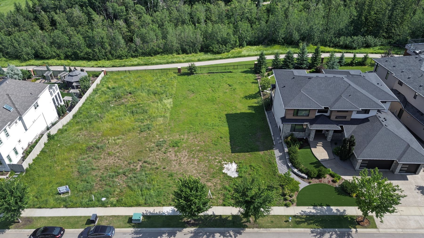 Lot 6 from the front, with a completed estate home on the right and open grass across the building pocket.