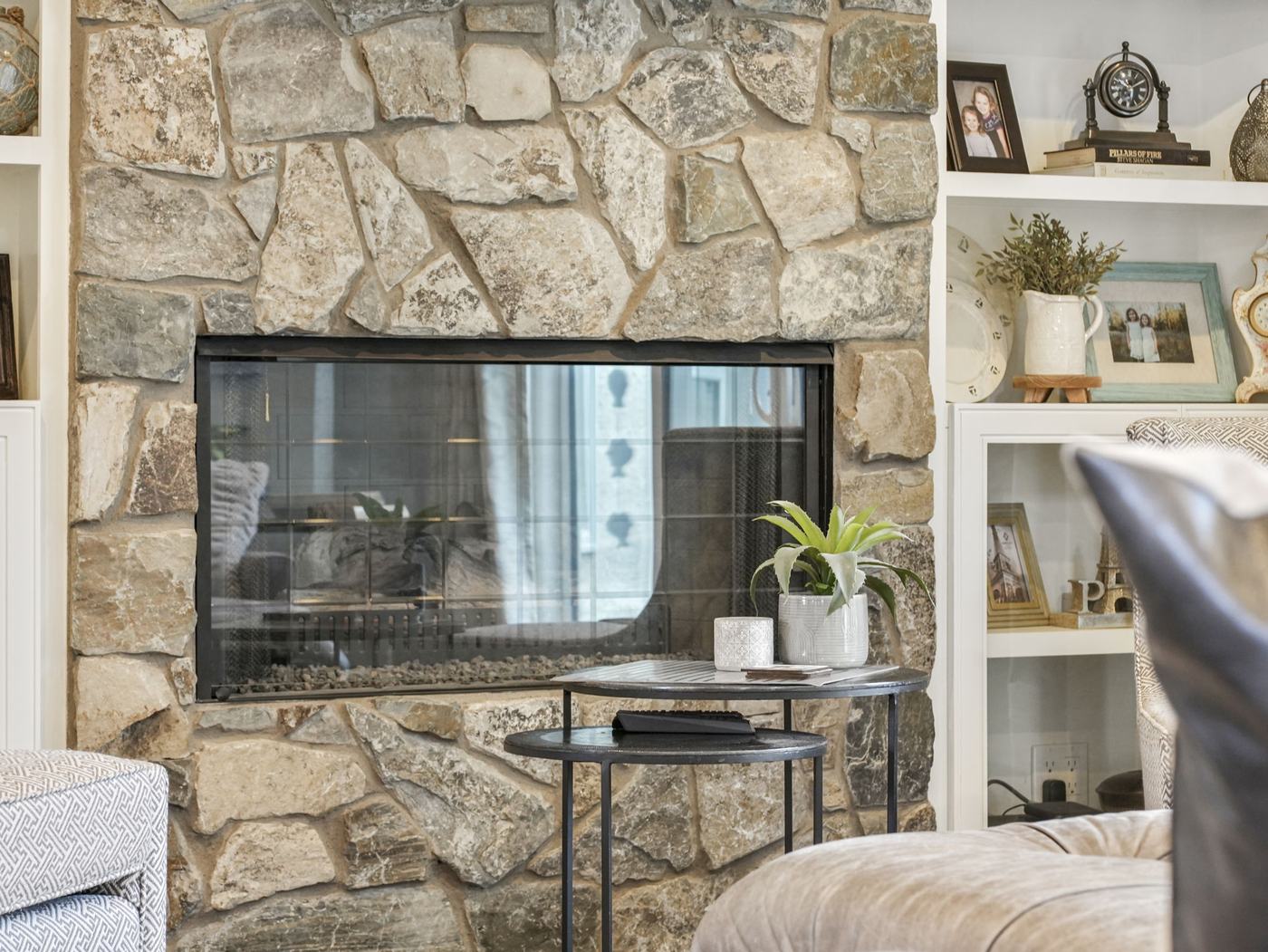 Close view of the hand-laid stone fireplace surround with a fire burning.
